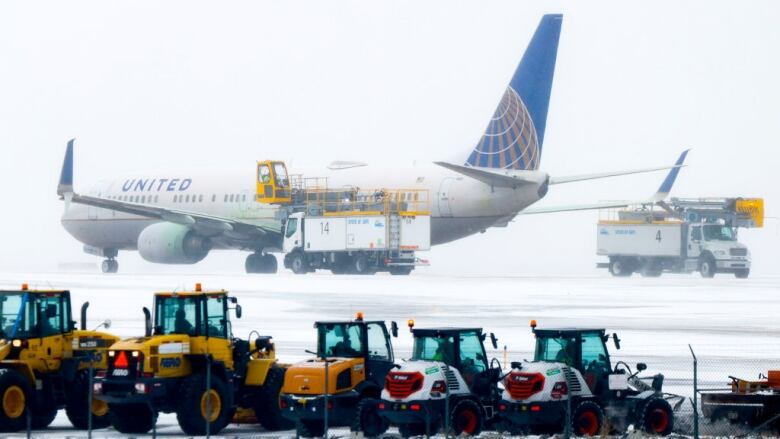 A large plane with small snowplows in the forefront.