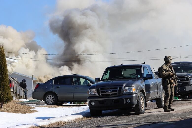 Heavily armoured officers stand by the burning house in Eskasoni