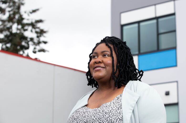 A portrait of a Black woman in a light polka dot dress and jacket.