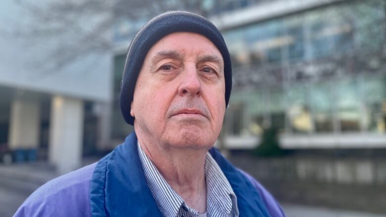 A man in a blue coat in front of city hall.