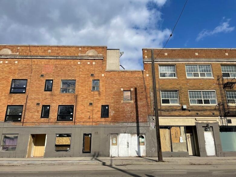 A three story brick building with new and boarded up windows.