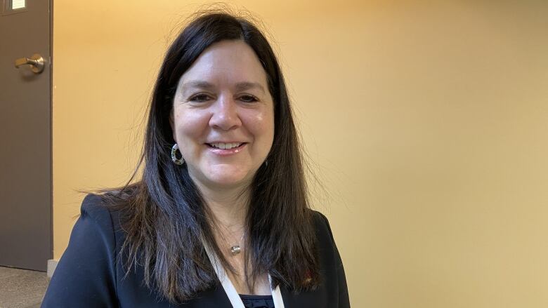 A portrait of a smiling woman standing in a room.