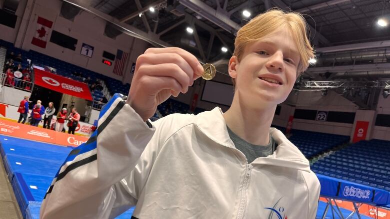 Cody Cyman - a trampolinist from Alberta - holds one of the specially made 'lucky loonies' his team has brought to spread good luck among competitors. 