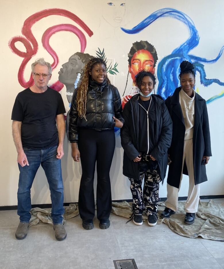 Four people stand in front of a wall.