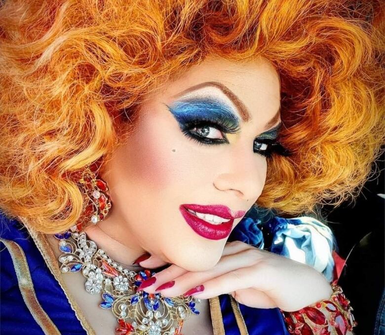 Portrait of a drag queen in a bright orange wig.