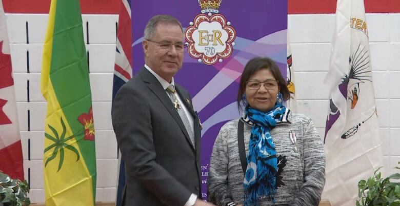 A woman standing next to a man with many flags behind them.