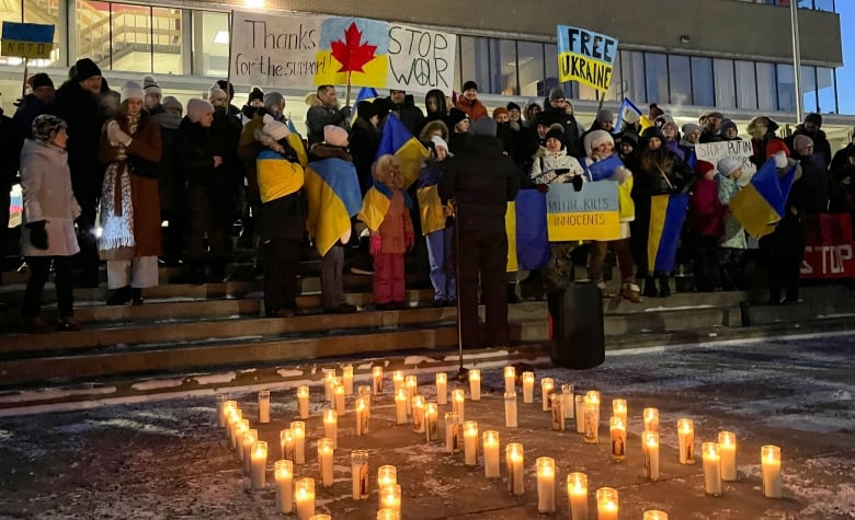 People stand on steps in front of lit candles during a vigil in Prince George, B.C.