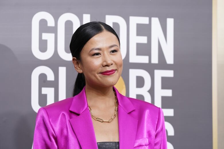 A woman wearing a fuschia jacket poses during an event.