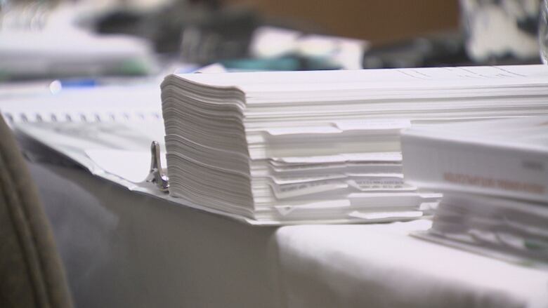 Piles of white paper documents on a white table