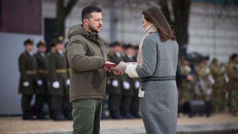 Ukrainian President Volodymyr Zelenskyy, left, awards a relative of a slain soldier a state Heroes of Ukraine medal during a commemorative event on the one-year anniversary of Russia's invasion in Kyiv, Ukraine on Friday, Feb. 24, 2023.