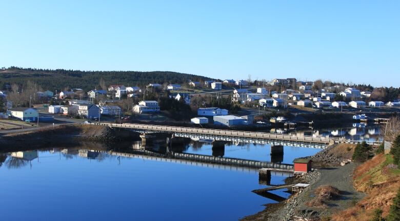 A bridge stands over water in front of houses.