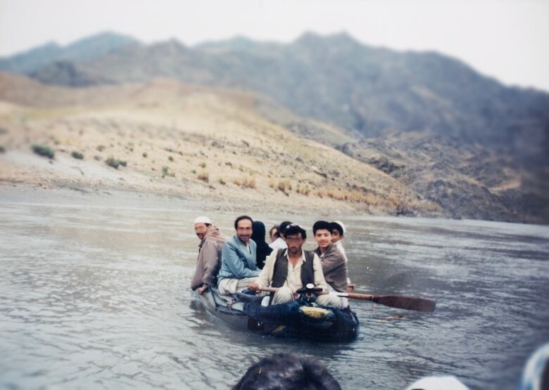 A small raft filled with 10 people (not all pictured) floats on a river at the Pakistan border.