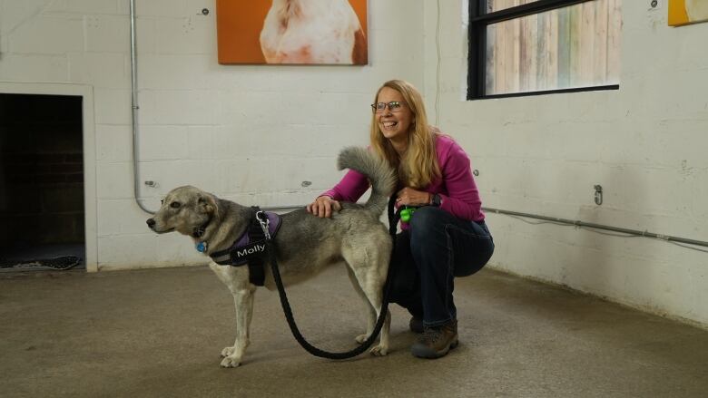 A woman crouching and petting her dog.