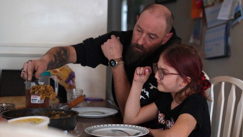 A man serves dinner on a spatula to a child.