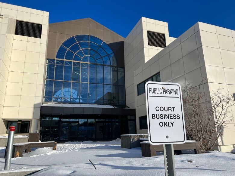 A sign reading, 'Public parking, court business only,' is seen in front of a large institutional building.