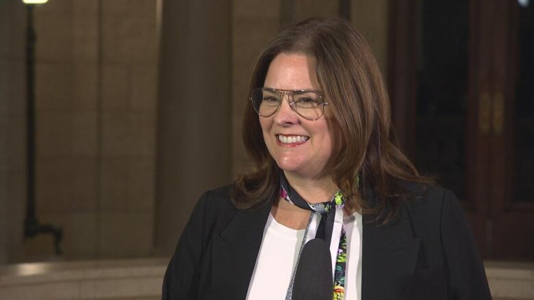 The premier, wearing a whiet shirt and a dark blue blazer, standing in the rotunda at the Manitoba Legislature.