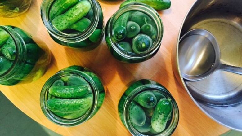 Jars of pickles sit on a counter.