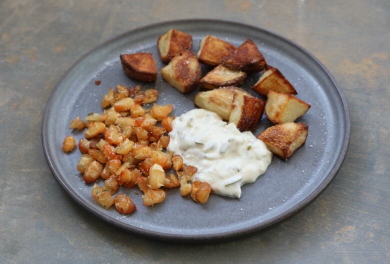 A dollop of mayonnaise sits on a plate with potatoes.