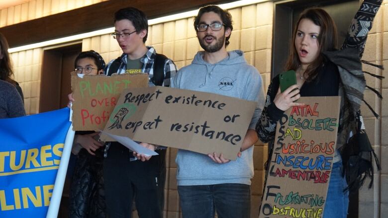 Students hold signs with statements about environmentalism painted on them.