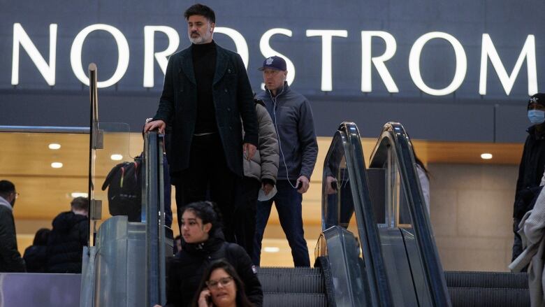 Shoppers walk past a department store in a mall.