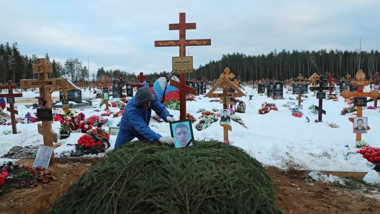 A worker places a portrait at the grave of Dmitry Menshikov, a mercenary for the private Russian military company Wagner Group, killed during the military conflict in Ukraine, in the Alley of Heroes at a cemetery in Saint Petersburg, Russia December 24, 2022. 