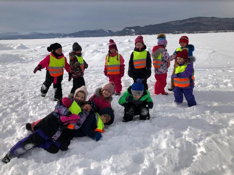 Young students play in the snow and smile for the camera.