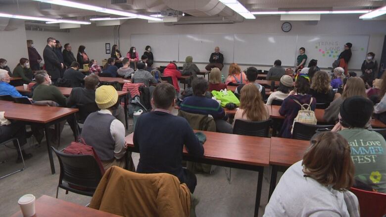 Dozens sit in a classroom at a university.