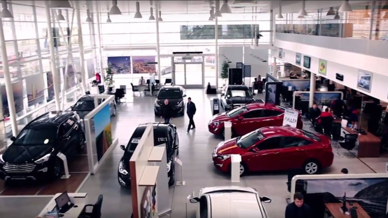 The interior of a car dealership with several cars parked in it. 