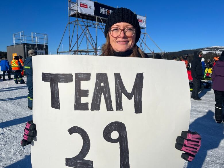 A woman holds a large white sign that says 'Team 29.'