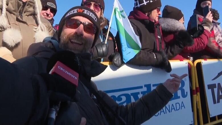 A man crouches near the starting ling of a snowmobile race.