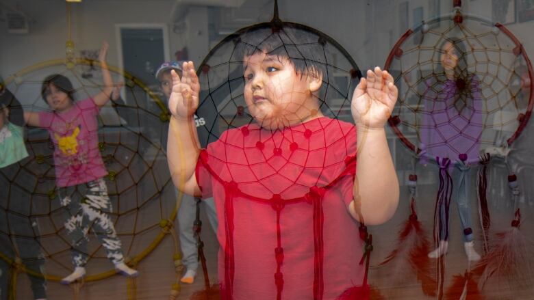 A multiple exposure photo shows dreamcatchers overlaid on children doing Zumba.