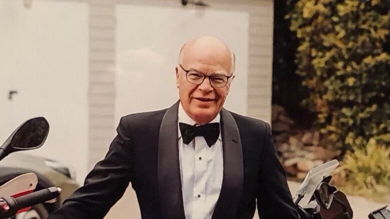 Man with glasses and tuxedo smiling at camera