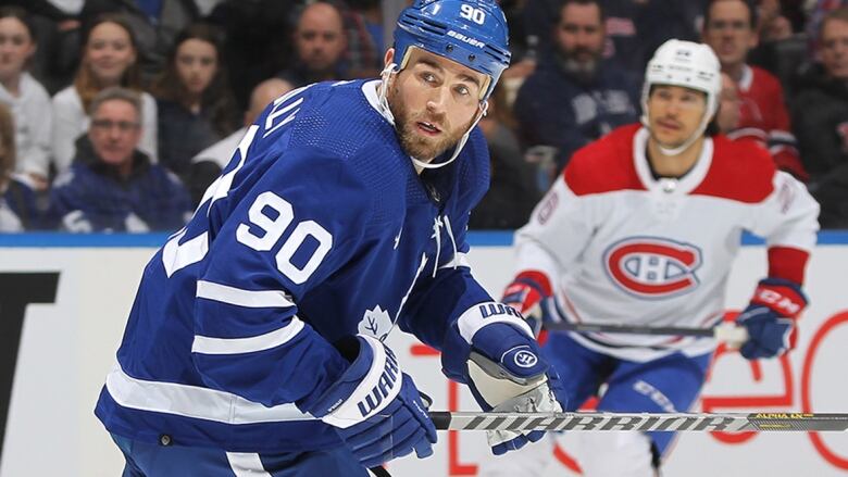 Male athlete looks back while skating up ice awaiting to receive a pass in an NHL game.