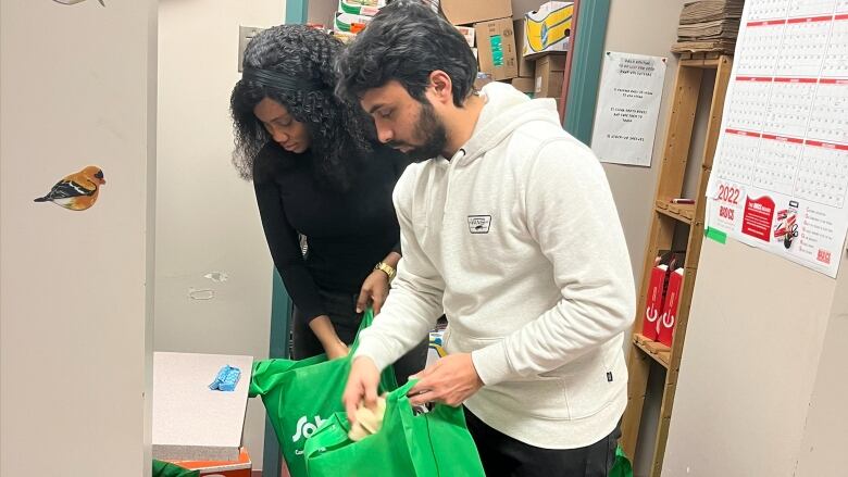 Two students are shown working at Cape Breton University's student-run food bank.