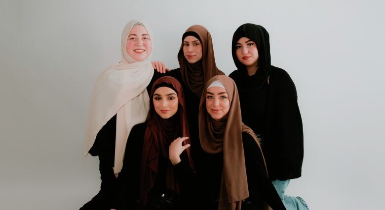 Five women pose for the camera in a studio setting, displaying their hijabs for company HYAT CO.