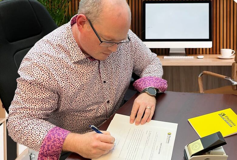 Man in dress shirt signs election document.