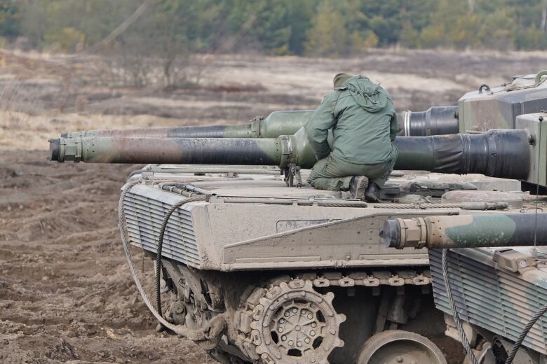 A soldier crouches on a Leopard tank in Poland