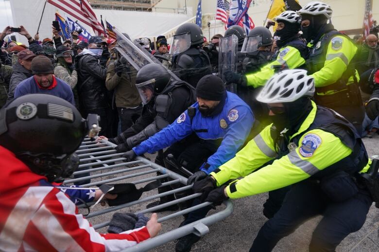 Police officers are shown battling with demonstrators as a barricade between them is pushed over.