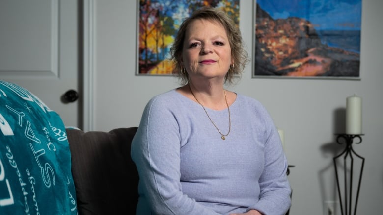 A woman sits in a room with colourful artwork.