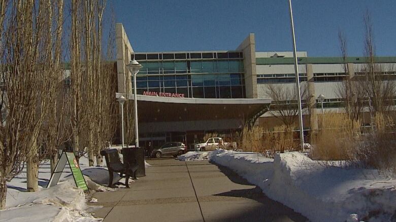 The concrete walkway into the Red Deer Regional Hospital Centre is shown on a sunny winter day. Red letters above the buildings awning read 