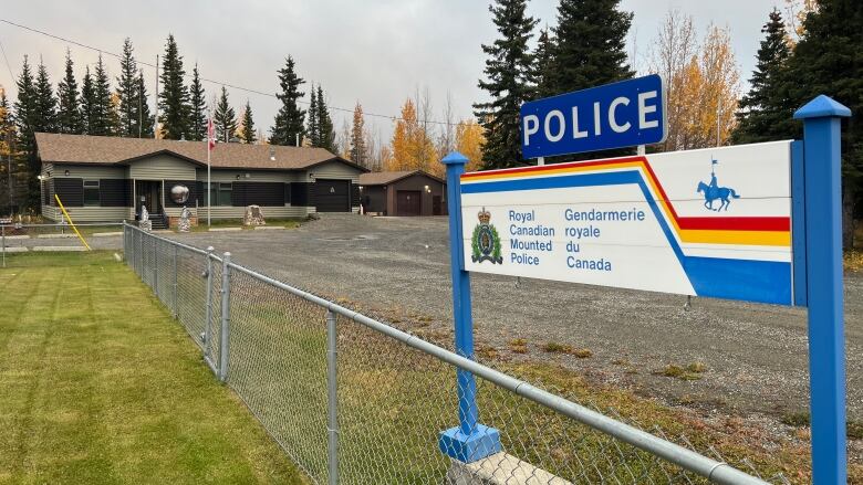 A sign for the Royal Canadian Mounted Police is seen alongside a fence in front of a building.