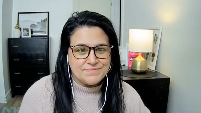 A woman is shown in a video call wearing headphones.