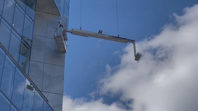 A window cleaners' scaffolding dangles from the side of a skyscraper.