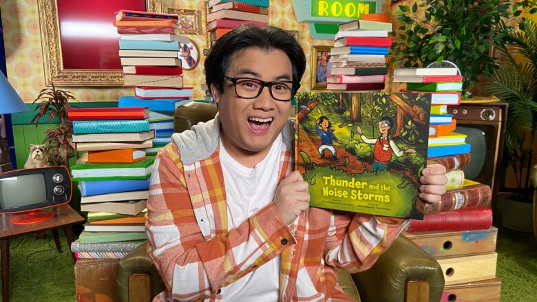 A man holds up a children's picture book, smiling.