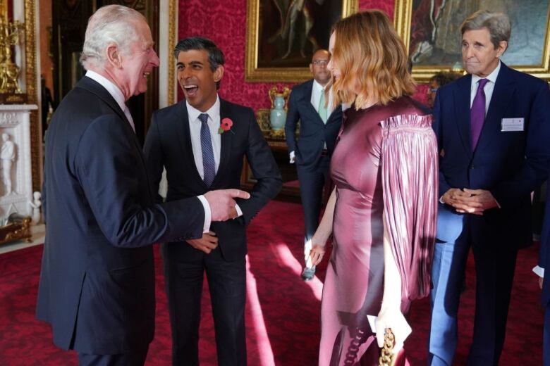 Four people stand at a reception as some of them laugh and speak.