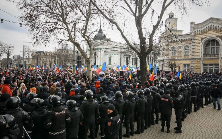 Riot police officers are seen standing at the edge of a crowd of protesters during an anti-government demonstration in Chisinau, Moldova, last month.