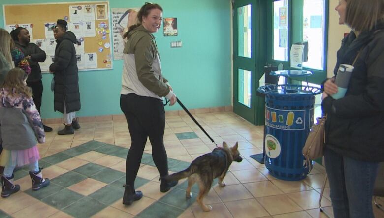 A woman is pictured walking a dog out of a building.