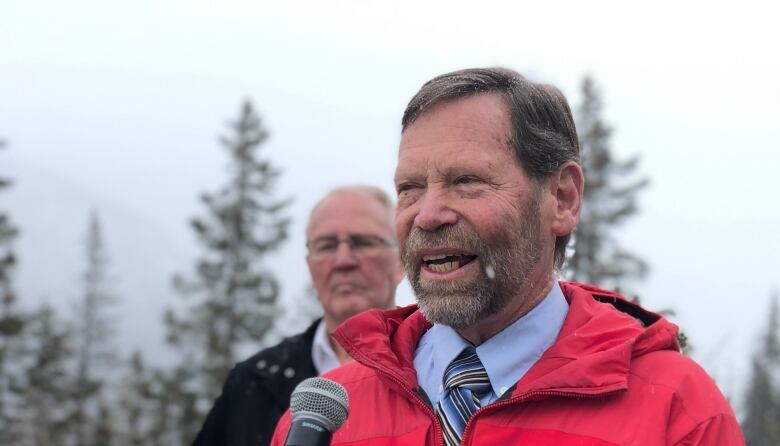 Doug Ritchie, vice president of Search and Rescue Association of Alberta, stands in the foreground while federalMinister of Emergency Preparedness Bill Blair stands behind him to the left, slightly out of focus.