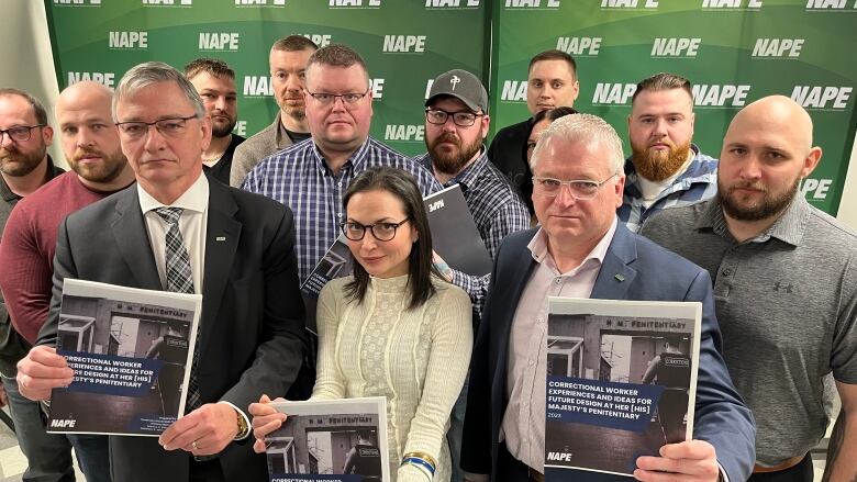 A group of correctional officers, posing with NAPE union leadership and a university professor who authored a study into working conditions at HMP.