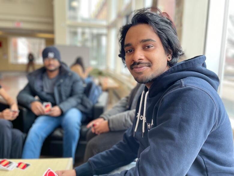 Ashwin Panthirupara Santosh, a first year student at UPEI, sits amongst friends playing a card game in the university student centre. 